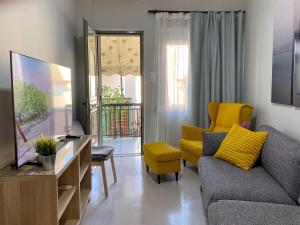 salon z kanapą i żółtym krzesłem w obiekcie Nasos Aegina Apartment w mieście Egina