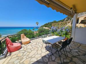 eine Terrasse mit einem Tisch, Stühlen und Meerblick in der Unterkunft Corfu Glyfada Beach Apartment 45 in Glyfada