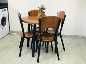 a wooden table with four chairs and a vase on it at Batoka Apartments in Lusaka