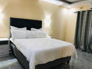 a bedroom with a large bed with white sheets and pillows at Batoka Apartments in Lusaka