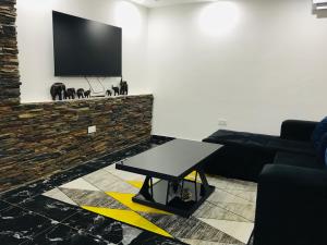 een woonkamer met een tafel en een flatscreen-tv bij Batoka Apartments in Lusaka