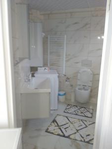 Baño blanco con lavabo y aseo en Kuzey apart, en Ezine