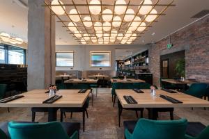 a restaurant with wooden tables and green chairs at Sandman Signature Glasgow Hotel in Glasgow