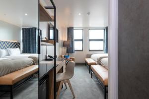 a hotel room with two beds and a desk at Sandman Signature Glasgow Hotel in Glasgow