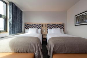 two beds sitting next to each other in a room at Sandman Signature Glasgow Hotel in Glasgow