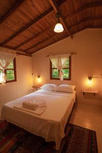 a bedroom with a large white bed with two windows at Alma Hotel Campestre in Santa Elena