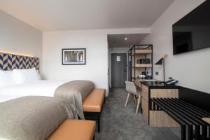 a hotel room with two beds and a desk at Sandman Signature Glasgow Hotel in Glasgow