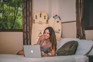 una mujer acostada en una cama con un portátil en Manglar Lodge, en San Carlos