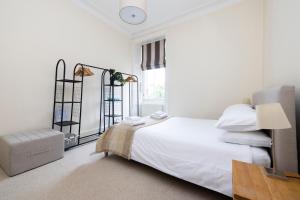 a white bedroom with a bed and a window at Tasteful 1-bedroom Apartment near Edinburgh Meadows in Edinburgh