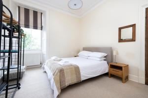 Tasteful 1-bedroom Apartment near Edinburgh Meadows في إدنبرة: غرفة نوم بيضاء بسرير وسلم