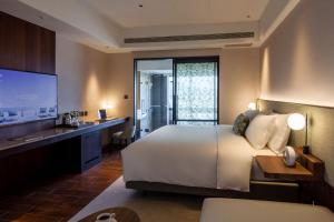 a bedroom with a bed and a desk and a television at Kilin Hotel, JiaoXi in Jiaoxi