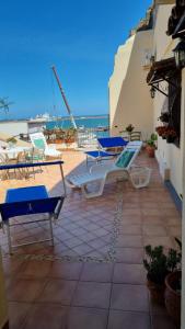 une terrasse avec des chaises bleues et blanches et l'océan dans l'établissement Sicily Coast, à Catane