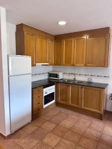 La cuisine est équipée d'un réfrigérateur blanc et de placards en bois. dans l'établissement Mountain Apartment: Pedraforca, à Saldes