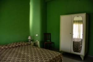 ヴィッラプッツにあるB&B DomuSannaの緑の壁のベッドルーム(ベッド1台、鏡付)