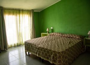 - une chambre verte avec un lit et un mur vert dans l'établissement B&B DomuSanna, à Villaputzu