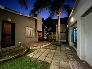 una casa con una palmera en el patio en Casa Bravo - Pilgrims Palace, en Pretoria