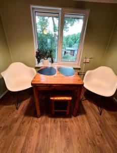 una mesa de madera con 2 sillas y una ventana en Retro bungalow en Liepāja