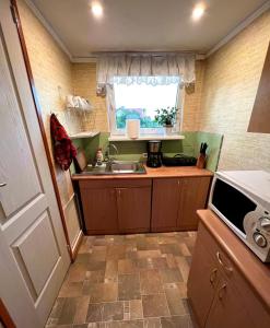 eine kleine Küche mit einem Waschbecken und einem Fenster in der Unterkunft Retro bungalow in Liepāja