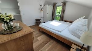 1 dormitorio con 1 cama y un jarrón de flores sobre una mesa en Tegernsee Chalet en Gmund am Tegernsee