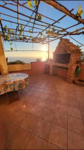 NebidaにあるVista Sul Pan di Zucchero - Nebida - Holiday Houseの石造りの暖炉とテーブル付きの屋外パティオ