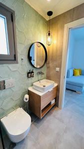 a bathroom with a sink and a toilet and a mirror at Arodo Suites in Iraklitsa