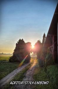 a dirt road in a field with the sun setting at Agroturystyka Karbowo in Brodnica