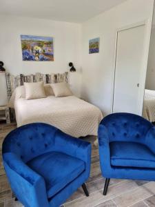 ein Schlafzimmer mit zwei blauen Stühlen und einem Bett in der Unterkunft Hébergement de vacances Chez Patrick et Patricia in Aubignan