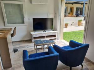 ein Wohnzimmer mit 2 blauen Stühlen und einem TV in der Unterkunft Hébergement de vacances Chez Patrick et Patricia in Aubignan