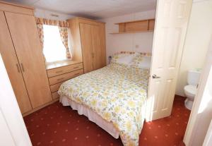 a small bedroom with a bed and a bathroom at Hedgehog Holiday Home in the countryside, 10 mins to Lligwy beach in Llandyfrydog