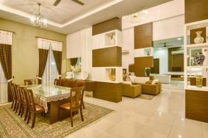 a dining room and living room with a table and chairs at Elshape Holiday HOME in Melaka
