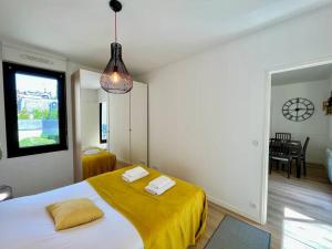 1 dormitorio con 1 cama con sábanas amarillas y ventana en Le Nid d'Erlon - Reims en Reims