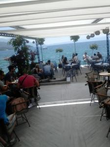 a group of people sitting at tables near the ocean at Orhidea House in Ohrid