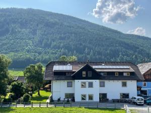 una casa blanca con paneles solares en ella con una montaña en Landhaus Lungau, en Sankt Michael im Lungau