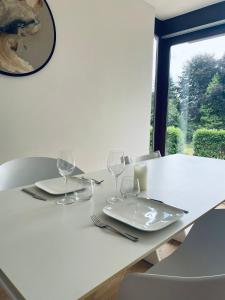 una mesa blanca con dos platos y copas de vino en Chalet au pays de Herve, en Herve