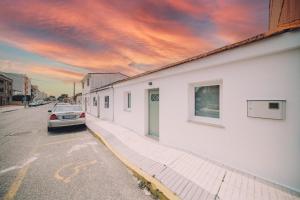 ein Auto, das auf einer Straße neben einem weißen Gebäude parkt in der Unterkunft Casa playa Las Sinas in Vilanova de Arousa