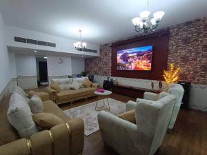 a living room with couches and a tv on a brick wall at شقة كبيرة وفخمة large and luxury two bedroom in Ajman 