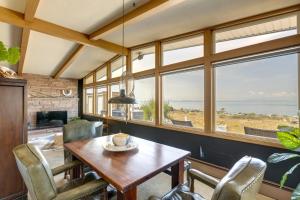 Point Roberts Cottage with Ocean Views and Hot Tub! في Point Roberts: غرفة طعام مع طاولة وكراسي ونوافذ