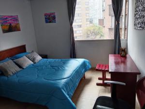 a bedroom with a bed and a desk and a window at Centro Histórico, candelaria -est Las aguas in Bogotá