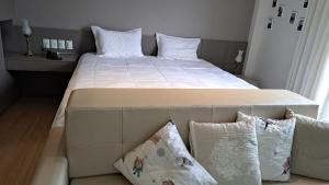 - un grand lit avec des draps et des oreillers blancs dans une chambre dans l'établissement Condomínio Vista Azul -CASA DOS CARDOSO, à Domingos Martins