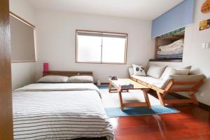 Panda Stay Okayama في أوكاياما: غرفة صغيرة بها سرير وأريكة