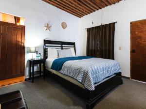a bedroom with a bed and a night stand with a table at OYO Posada Del Pescador in Cabo San Lucas