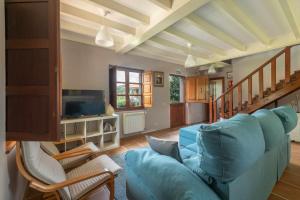 un salon avec un canapé bleu et une télévision dans l'établissement Vivienda Vacacional La Cortina, à Meré