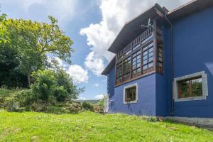 a blue house with a green field next to it at Vivienda Vacacional La Cortina in Meré