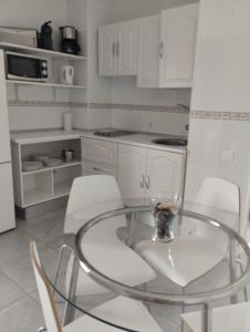 una cucina con tavolo in vetro e sedie bianche di PLAYA DEL INGLES-MASPALOMAS a Playa del Ingles