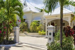 a house with a gate and palm trees at Rock Ridge by Barbados Sothebys International Realty in Saint Peter