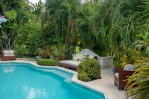 a swimming pool in a yard with benches and trees at Rock Ridge by Barbados Sothebys International Realty in Saint Peter