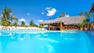 uma piscina de resort com cadeiras e um edifício com telhado de palha em Mini Hotel em Jericoacoara