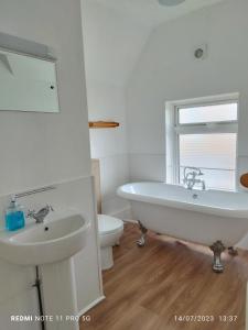 La salle de bains est pourvue d'une baignoire, d'un lavabo et de toilettes. dans l'établissement Blue Palms, à Bournemouth