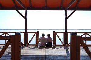 dwoje ludzi siedzących w doku patrzących na wodę w obiekcie Siwy Dom w Turawie