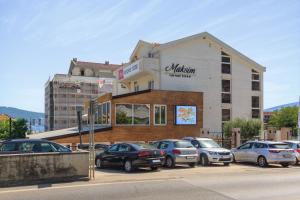 a building with cars parked in a parking lot at Hotel Maksim in Herceg-Novi